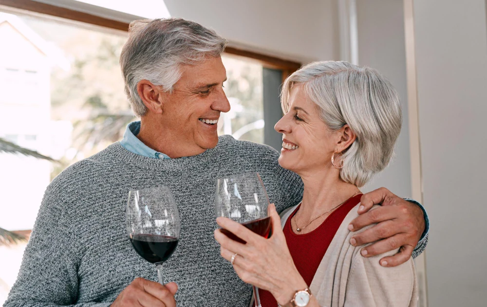 A smiling woman and man over 50 enjoying wine together at home