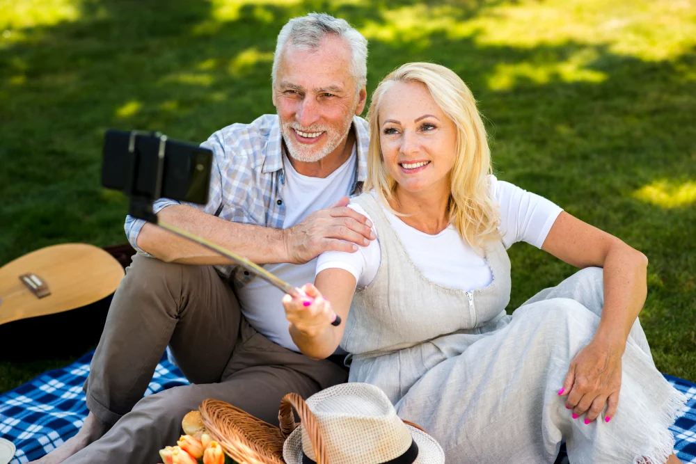 A smiling older couple taking a photo in a park