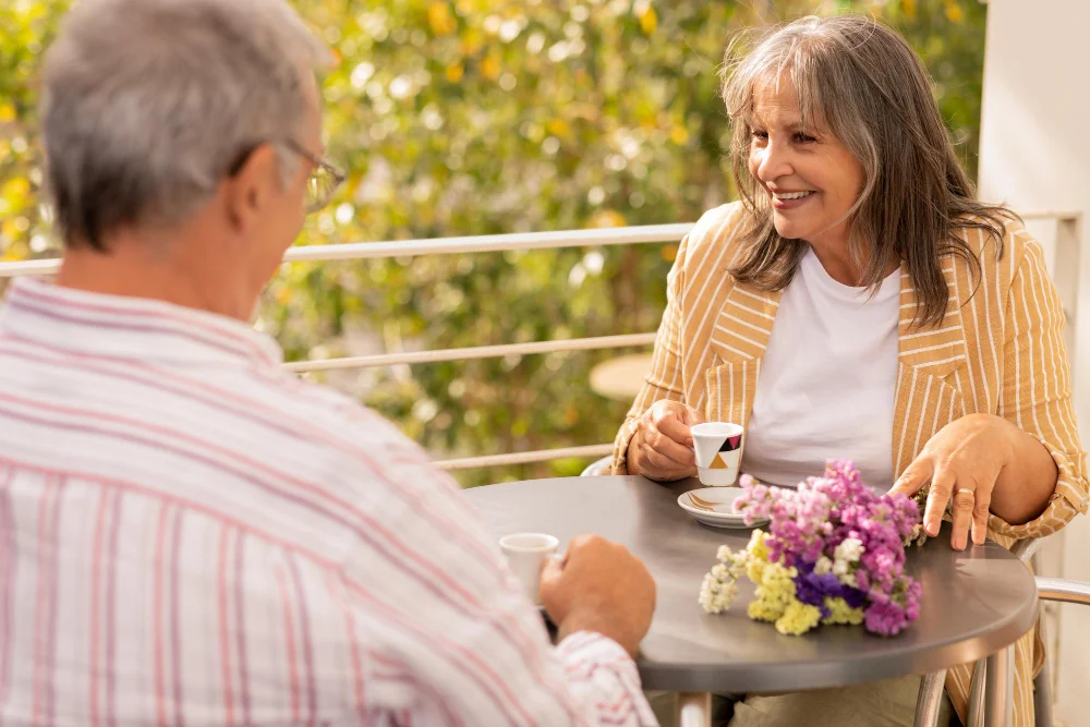 A woman over 60 talking over coffee on a sunny terrace